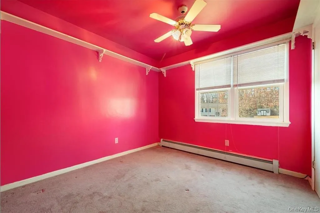 Unfurnished room featuring a baseboard radiator, carpet floors, and ceiling fan Unfurnished room featuring a baseboard radiator, carpet floors, and ceiling fan