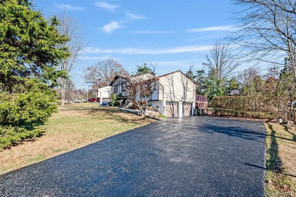 View of side of home featuring driveway, a yard, and an attached garage View of side of home featuring driveway, a yard, and an attached garage