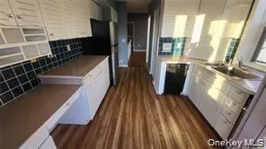 Kitchen with white cabinets, dark wood-style floors, freestanding refrigerator, and backsplash Kitchen with white cabinets, dark wood-style floors, freestanding refrigerator, and backsplash