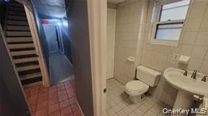 Bathroom featuring light tile patterned flooring and tile walls Bathroom featuring light tile patterned flooring and tile walls