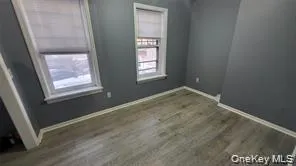 Unfurnished room featuring baseboards and dark wood-style floors Unfurnished room featuring baseboards and dark wood-style floors
