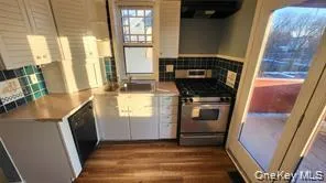 Kitchen with stainless steel range, dark wood-style floors, tasteful backsplash, and light countertops Kitchen with stainless steel range, dark wood-style floors, tasteful backsplash, and light countertops