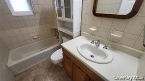 Full bath with tile walls, vanity, and shower / washtub combination Full bath with tile walls, vanity, and shower / washtub combination