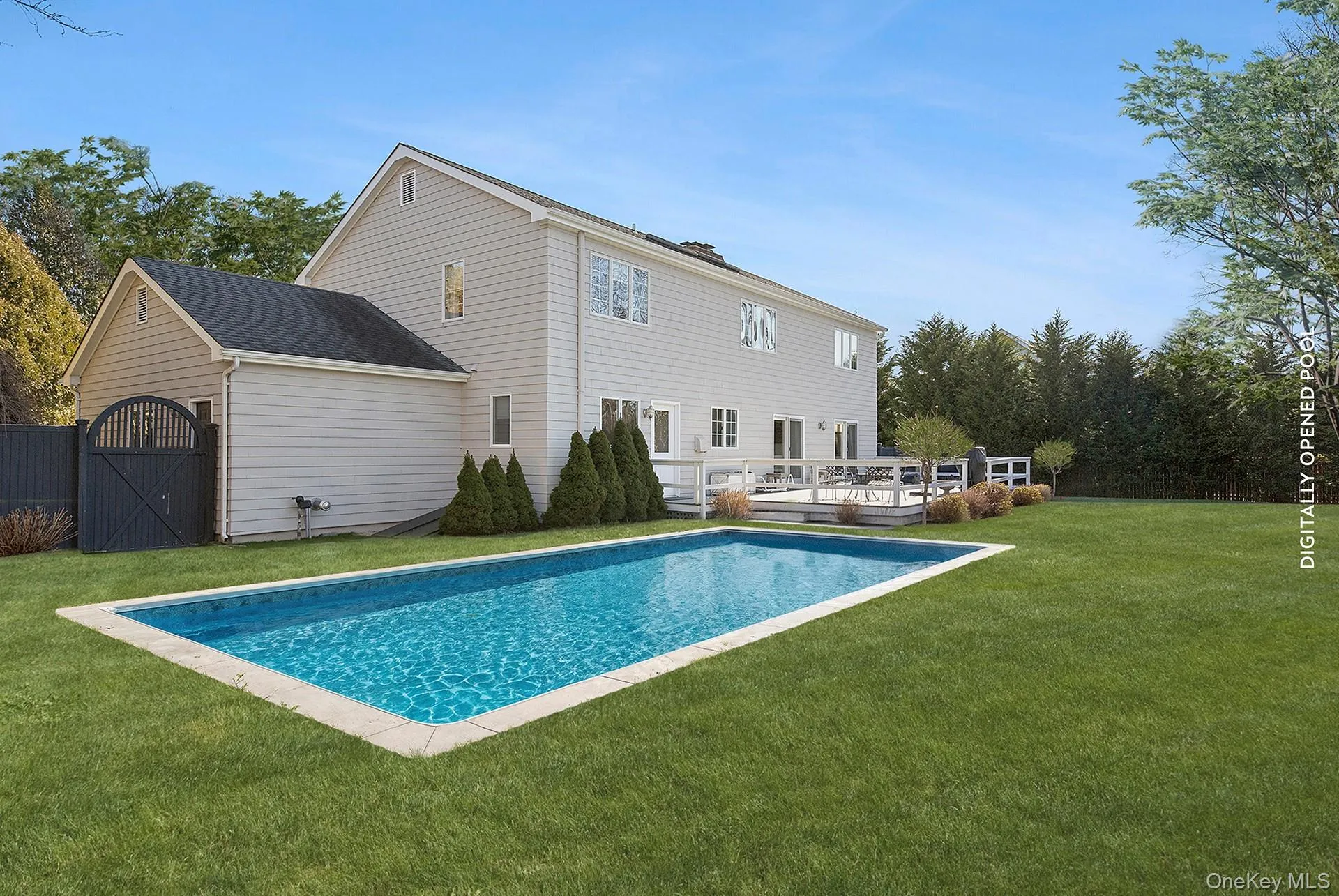 Outdoor pool with a lawn, a wooden deck, and a gate Outdoor pool with a lawn, a wooden deck, and a gate