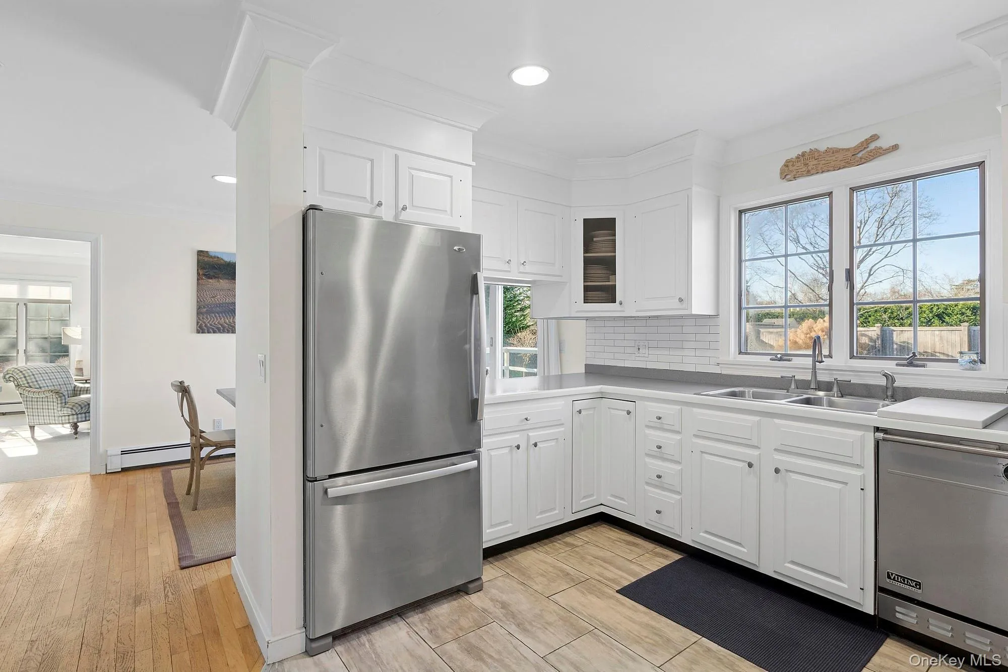 Kitchen featuring appliances with stainless steel finishes, ornamental molding, white cabinets, wood finish floors, and backsplash Kitchen featuring appliances with stainless steel finishes, ornamental molding, white cabinets, wood finish floors, and backsplash