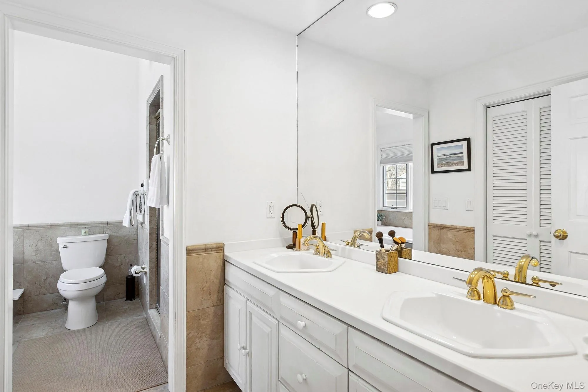 Full bathroom with double vanity, tile walls, wainscoting, a closet, and recessed lighting Full bathroom with double vanity, tile walls, wainscoting, a closet, and recessed lighting