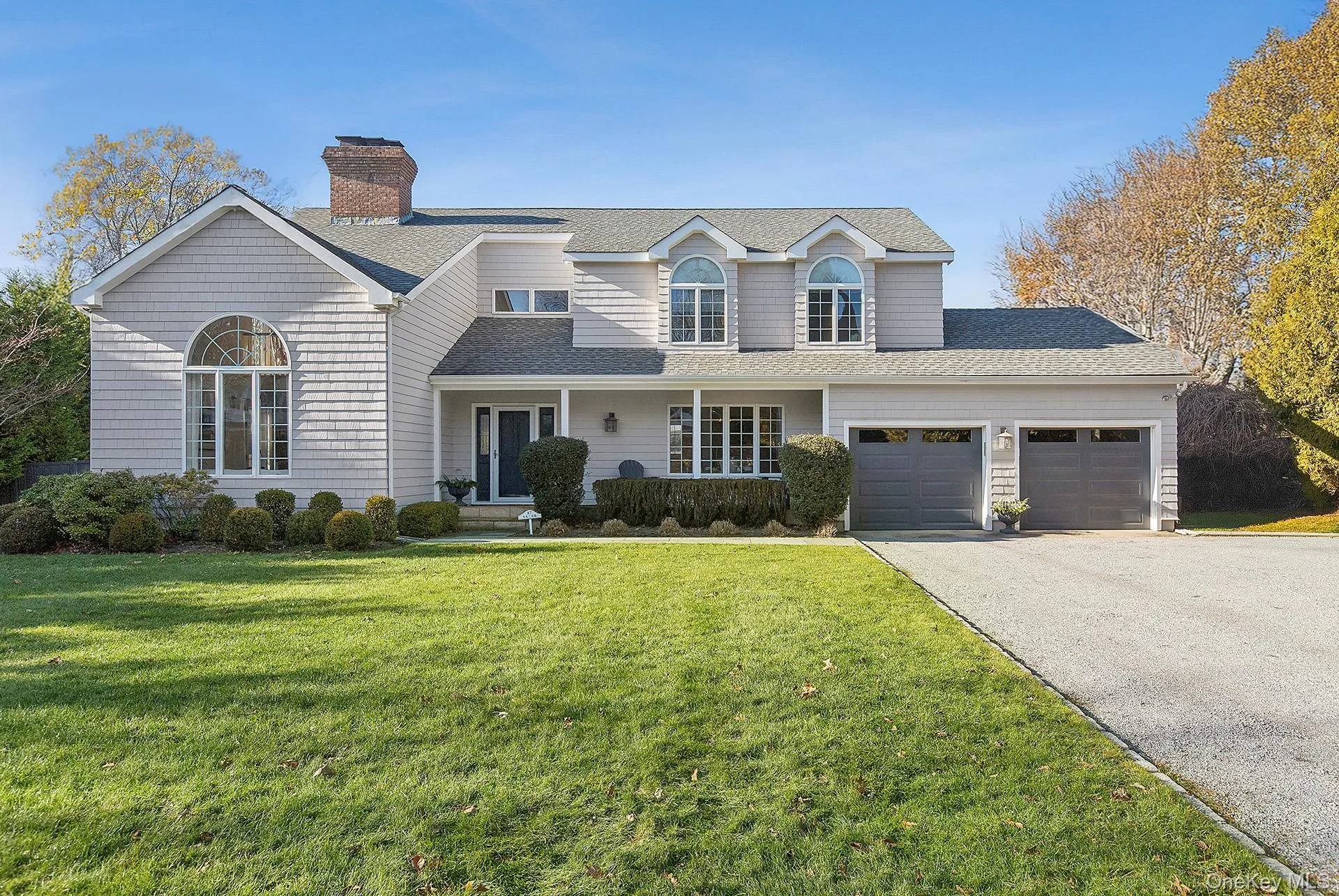 Traditional-style house with a porch, roof with shingles, a front lawn, asphalt driveway, and a chimney Traditional-style house with a porch, roof with shingles, a front lawn, asphalt driveway, and a chimney