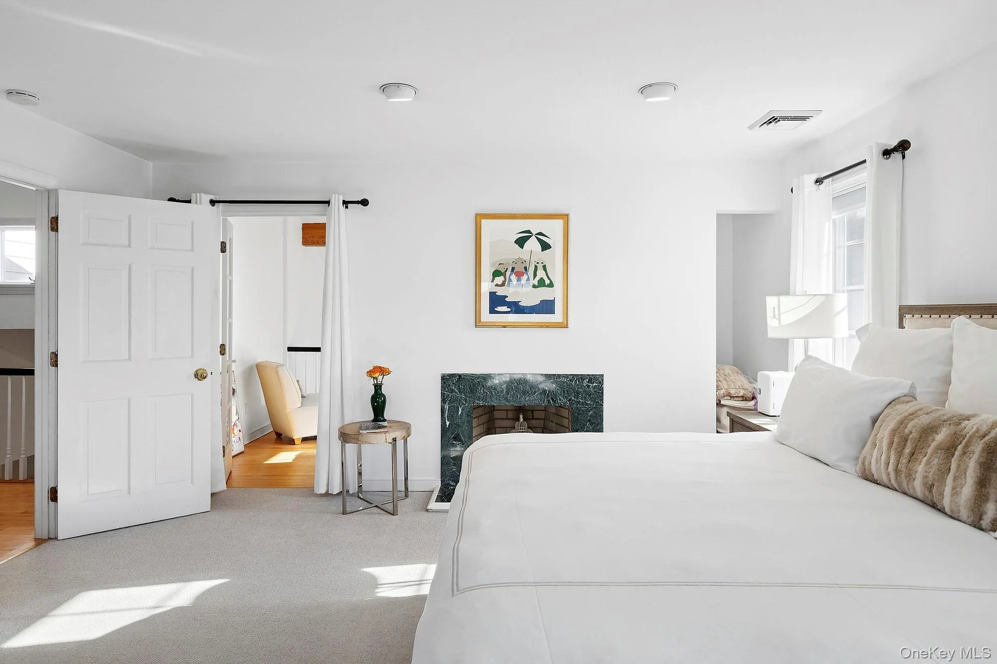 Carpeted bedroom featuring multiple windows and ensuite bath Carpeted bedroom featuring multiple windows and ensuite bath