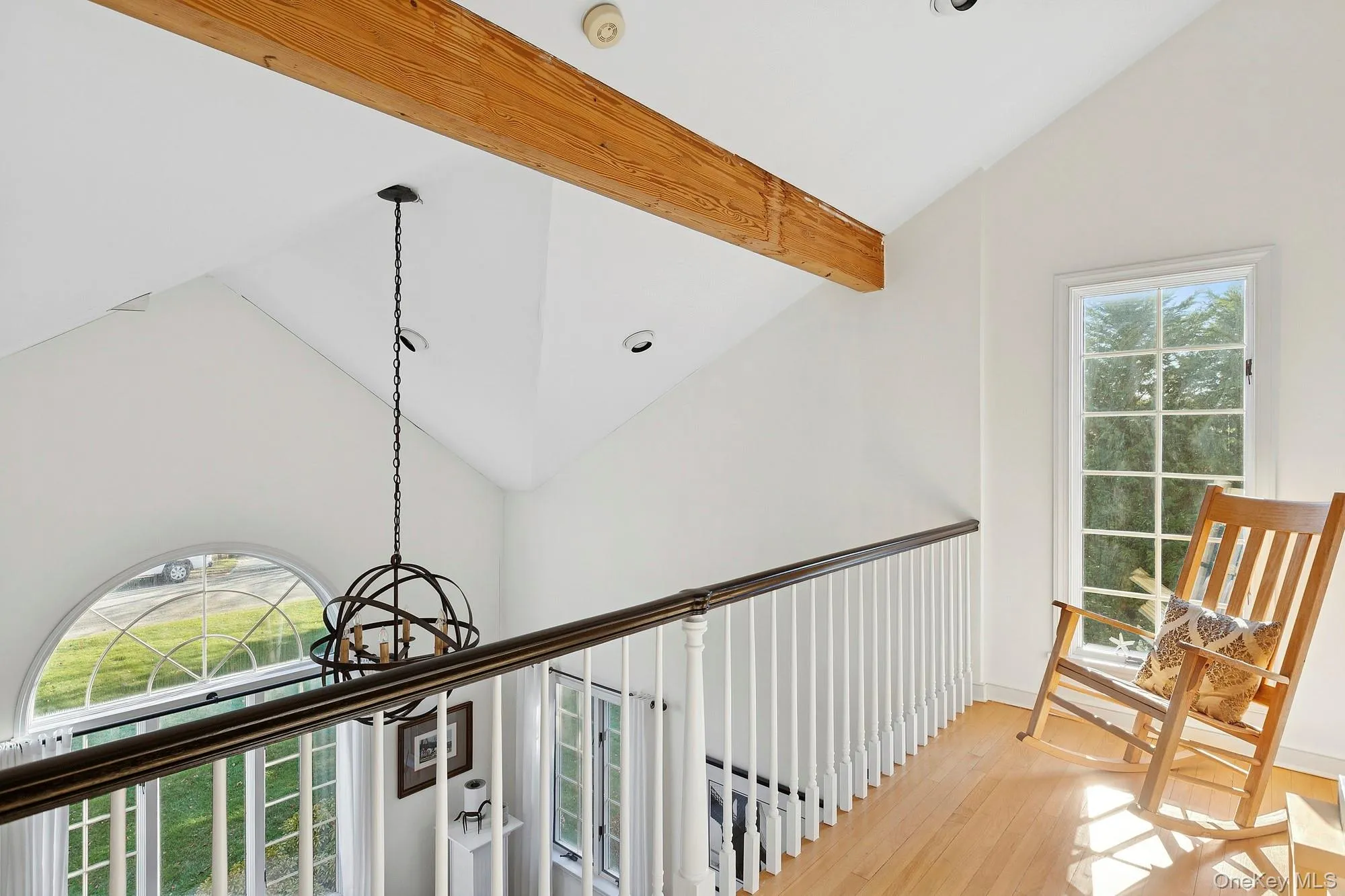 Hallway with healthy amount of natural light, high vaulted ceiling, light wood-style flooring, and a chandelier Hallway with healthy amount of natural light, high vaulted ceiling, light wood-style flooring, and a chandelier