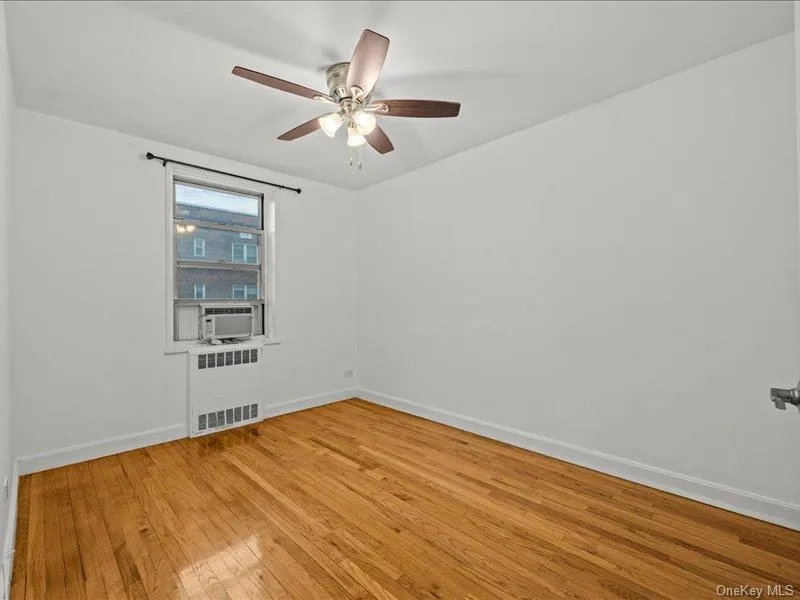 Empty room featuring radiator, light wood-type flooring, and ceiling fan Empty room featuring radiator, light wood-type flooring, and ceiling fan