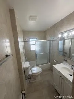 Bathroom with vanity, enclosed tub / shower combo, and tile walls Bathroom with vanity, enclosed tub / shower combo, and tile walls