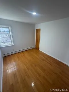 Spare room with wood finished floors, a baseboard heating unit, and recessed lighting Spare room with wood finished floors, a baseboard heating unit, and recessed lighting