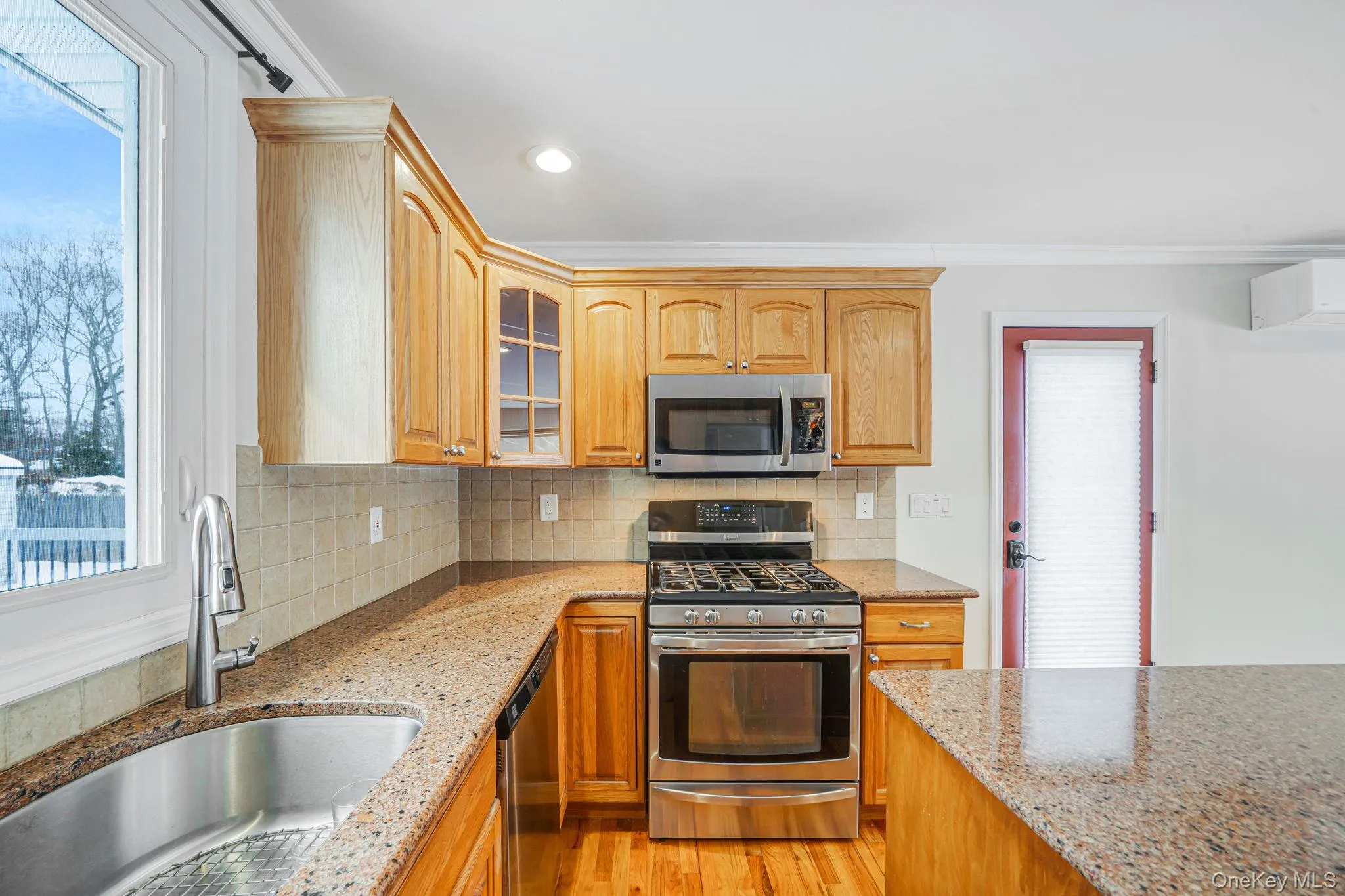 Kitchen with healthy amount of natural light, stainless steel appliances, glass cabinets with lighting, ornamental molding, and recessed lighting Kitchen with healthy amount of natural light, stainless steel appliances, glass cabinets with lighting, ornamental molding, and recessed lighting
