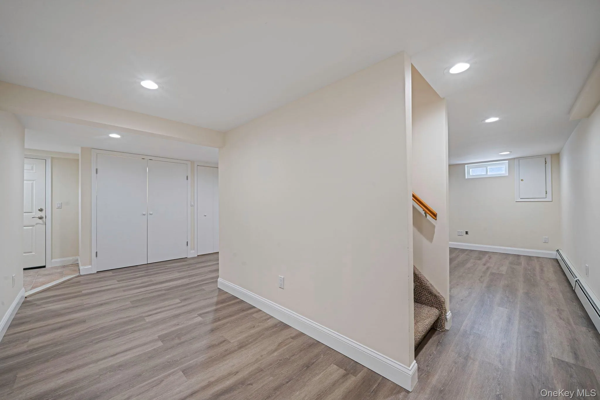 Basement featuring light wood finished floors, recessed lighting, stairs, and baseboard heating. Basement featuring light wood finished floors, recessed lighting, stairs, and baseboard heating.