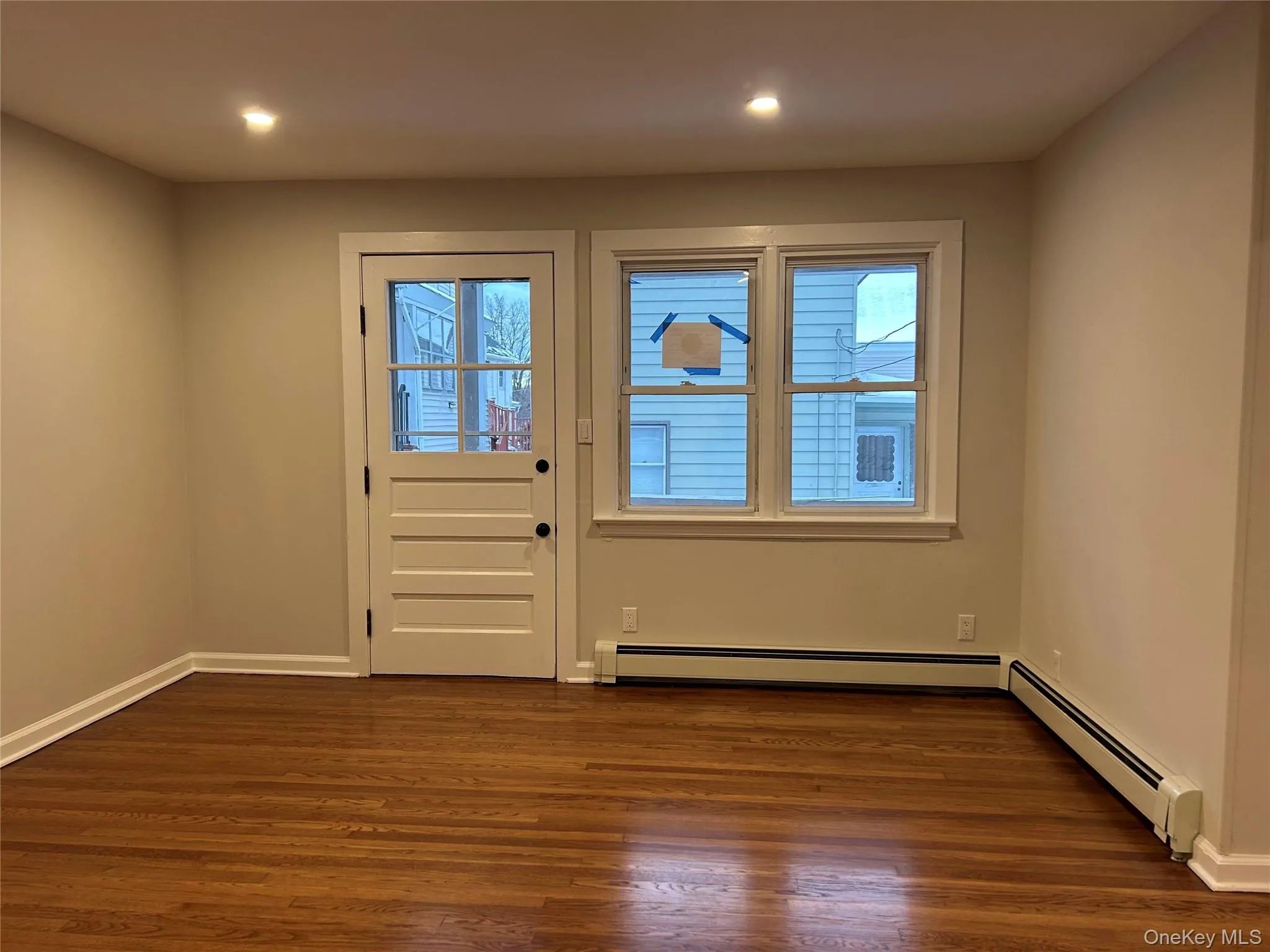 Living room featuring healthy amount of natural light, wood finished floors, a baseboard radiator, and recessed lighting Living room featuring healthy amount of natural light, wood finished floors, a baseboard radiator, and recessed lighting