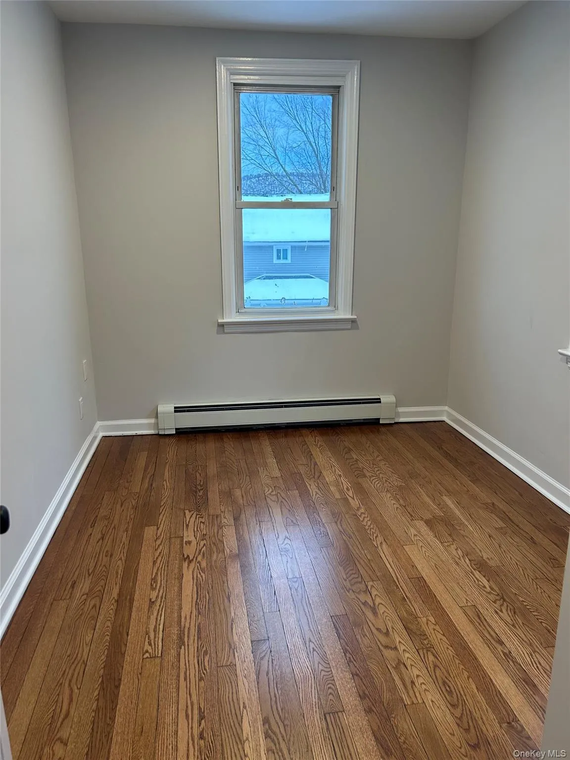 Bedroom featuring a baseboard radiator and dark wood finished floors Bedroom featuring a baseboard radiator and dark wood finished floors