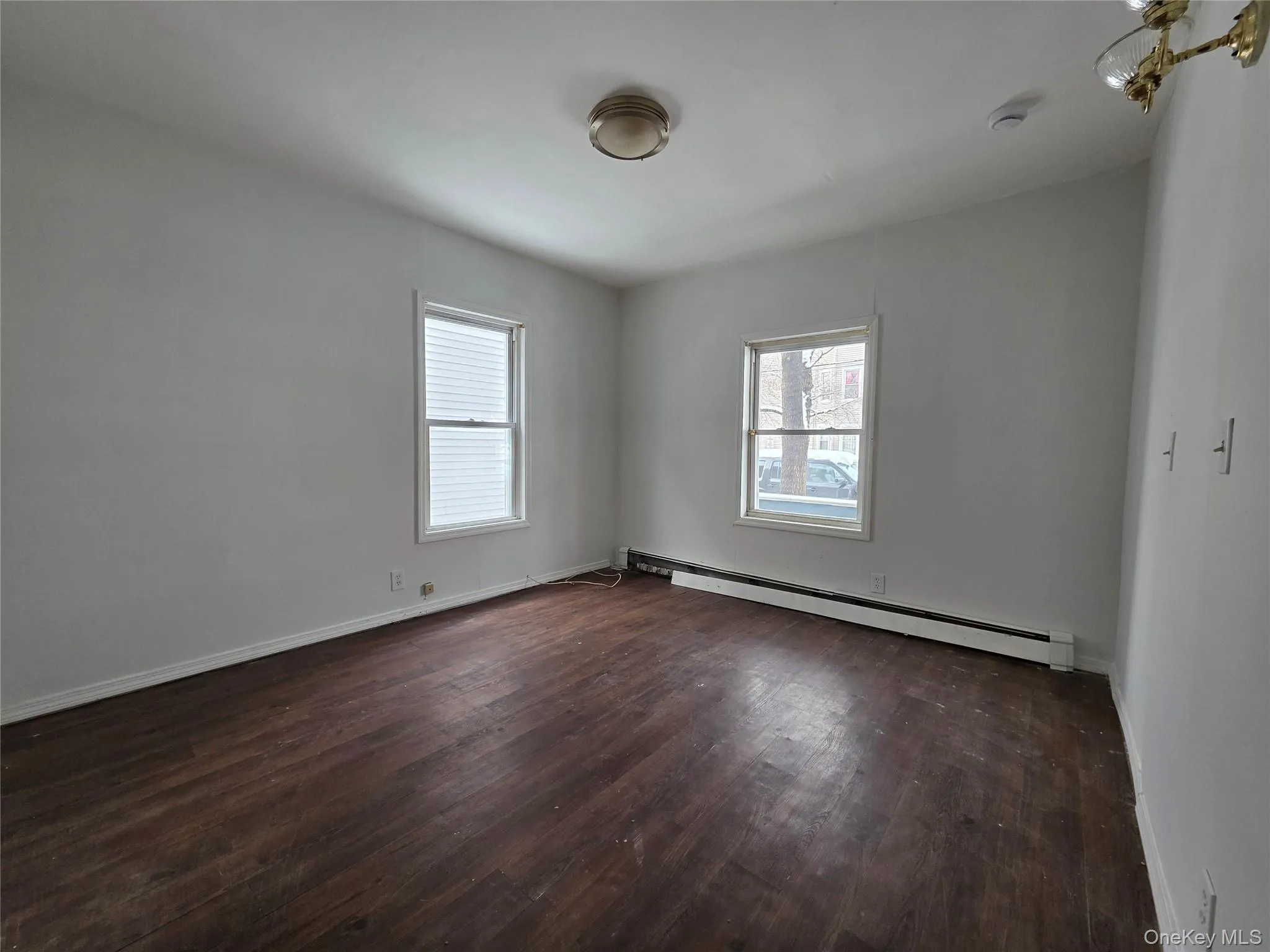 Unfurnished room featuring a baseboard heating unit and dark wood-type flooring Unfurnished room featuring a baseboard heating unit and dark wood-type flooring