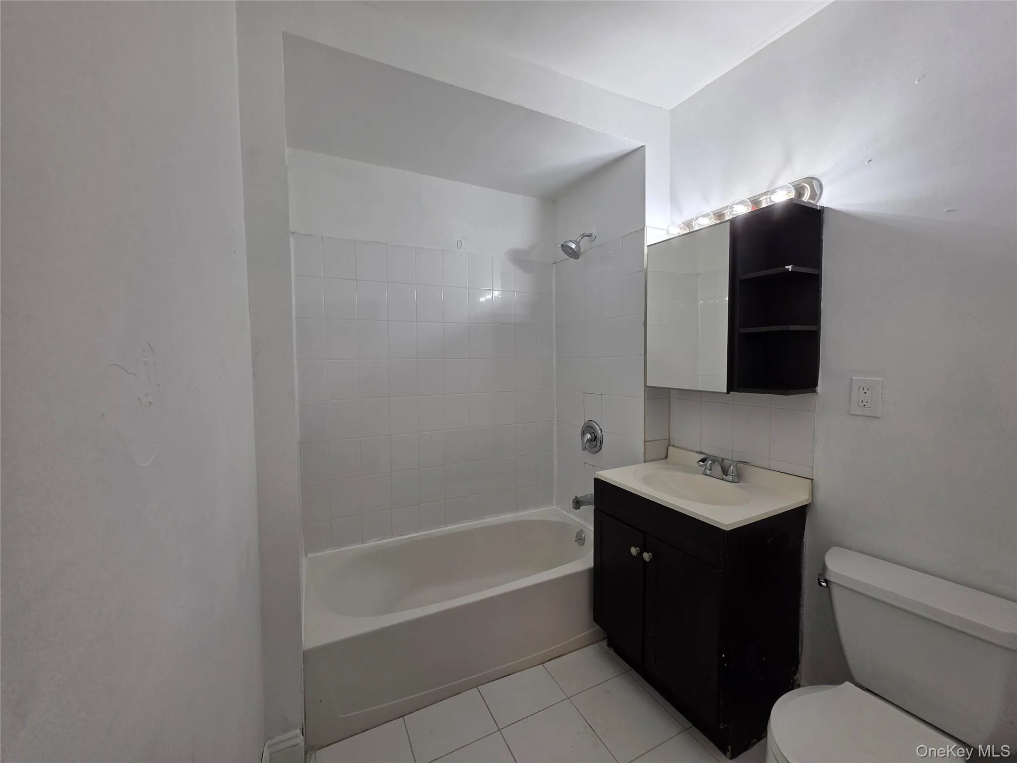Bathroom featuring vanity, shower combination, and light tile patterned floors Bathroom featuring vanity, shower combination, and light tile patterned floors