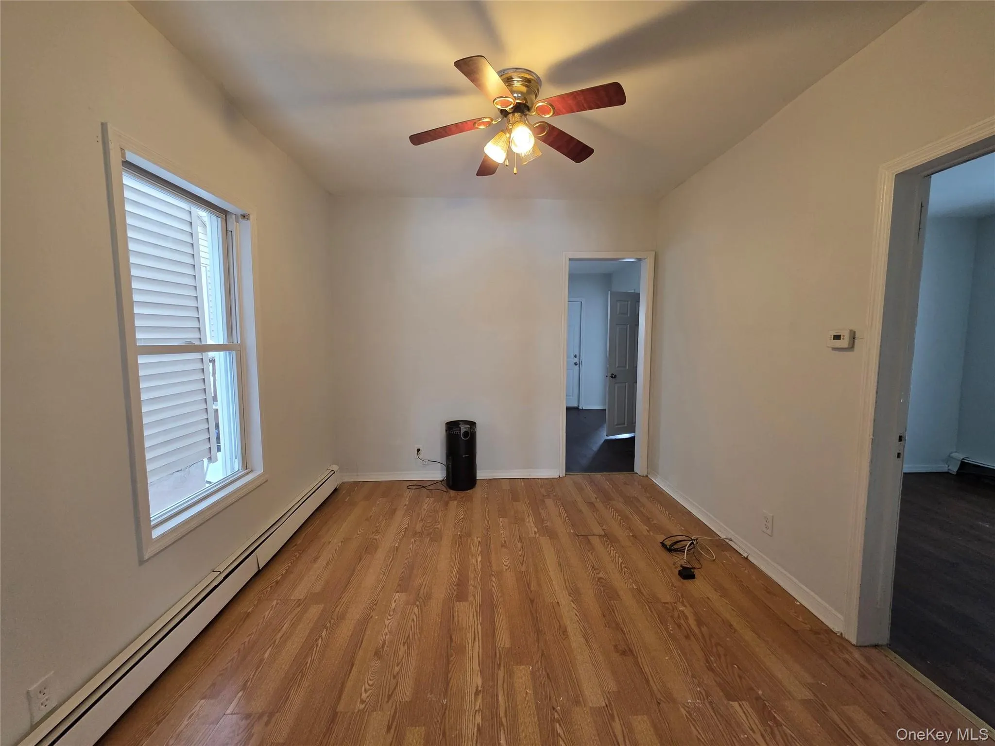 Spare room with a baseboard radiator, light wood-style floors, and a ceiling fan Spare room with a baseboard radiator, light wood-style floors, and a ceiling fan
