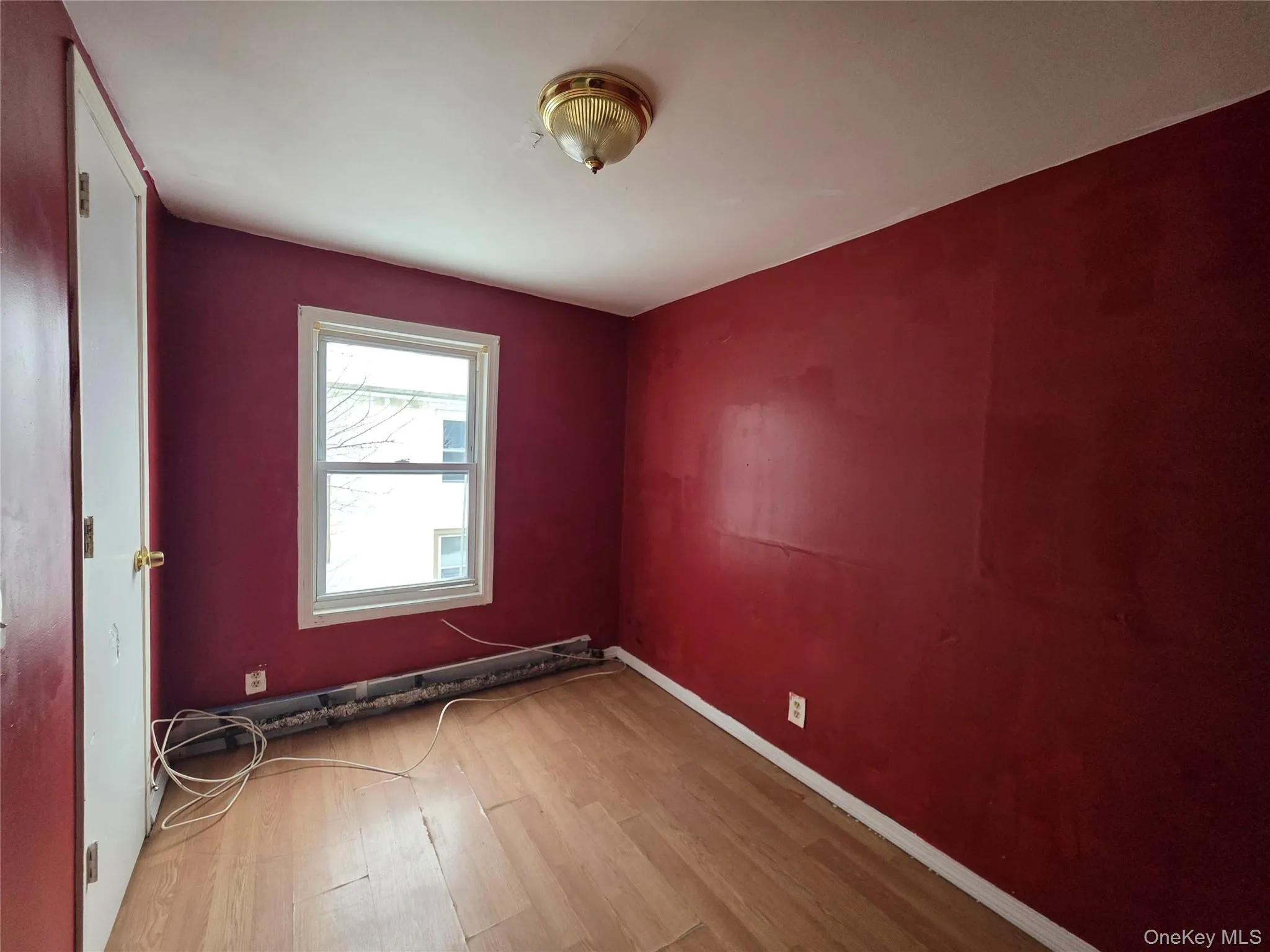 Empty room with wood finished floors and a baseboard radiator Empty room with wood finished floors and a baseboard radiator