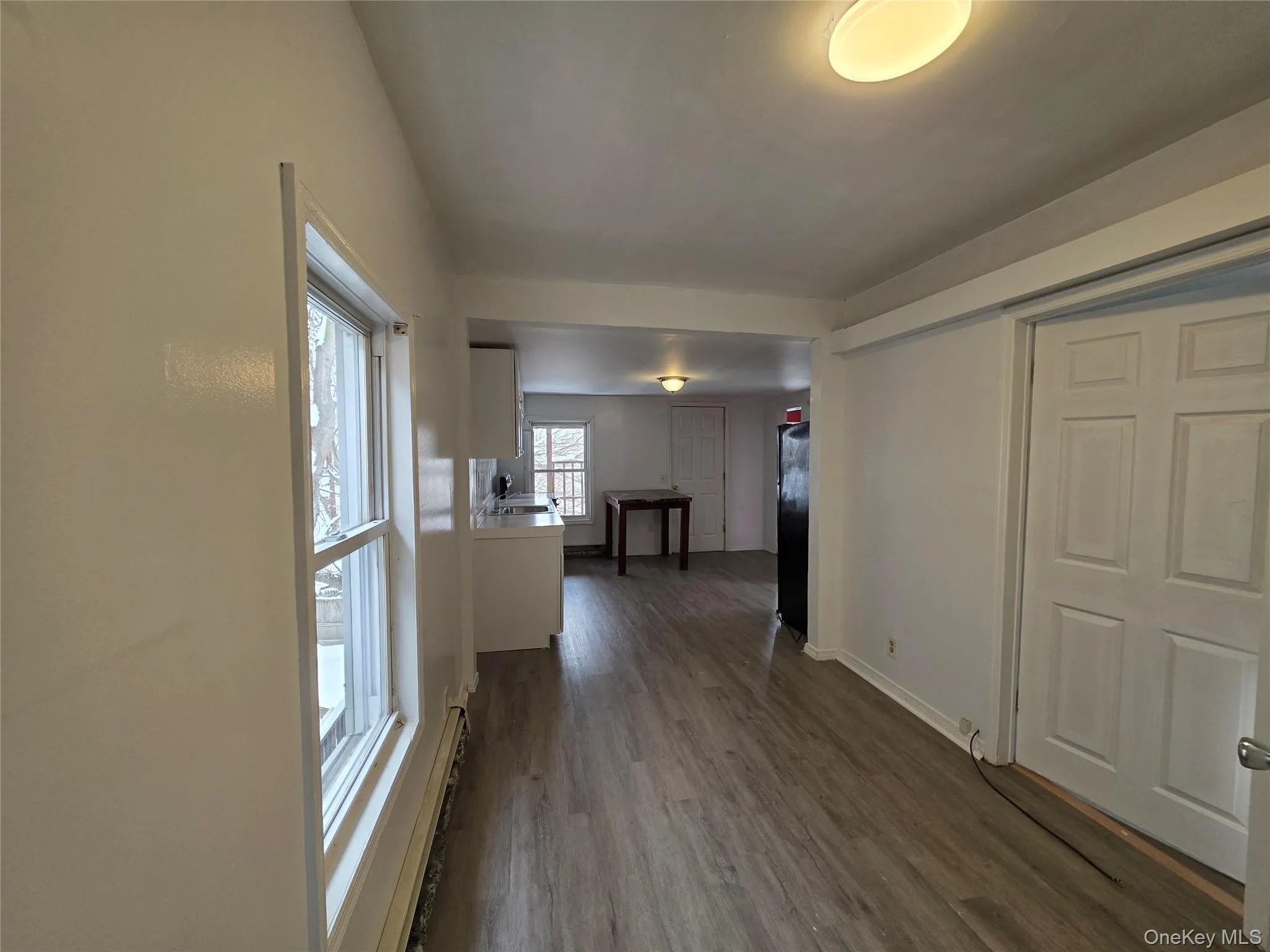 Hall featuring a baseboard heating unit and dark wood-style floors Hall featuring a baseboard heating unit and dark wood-style floors