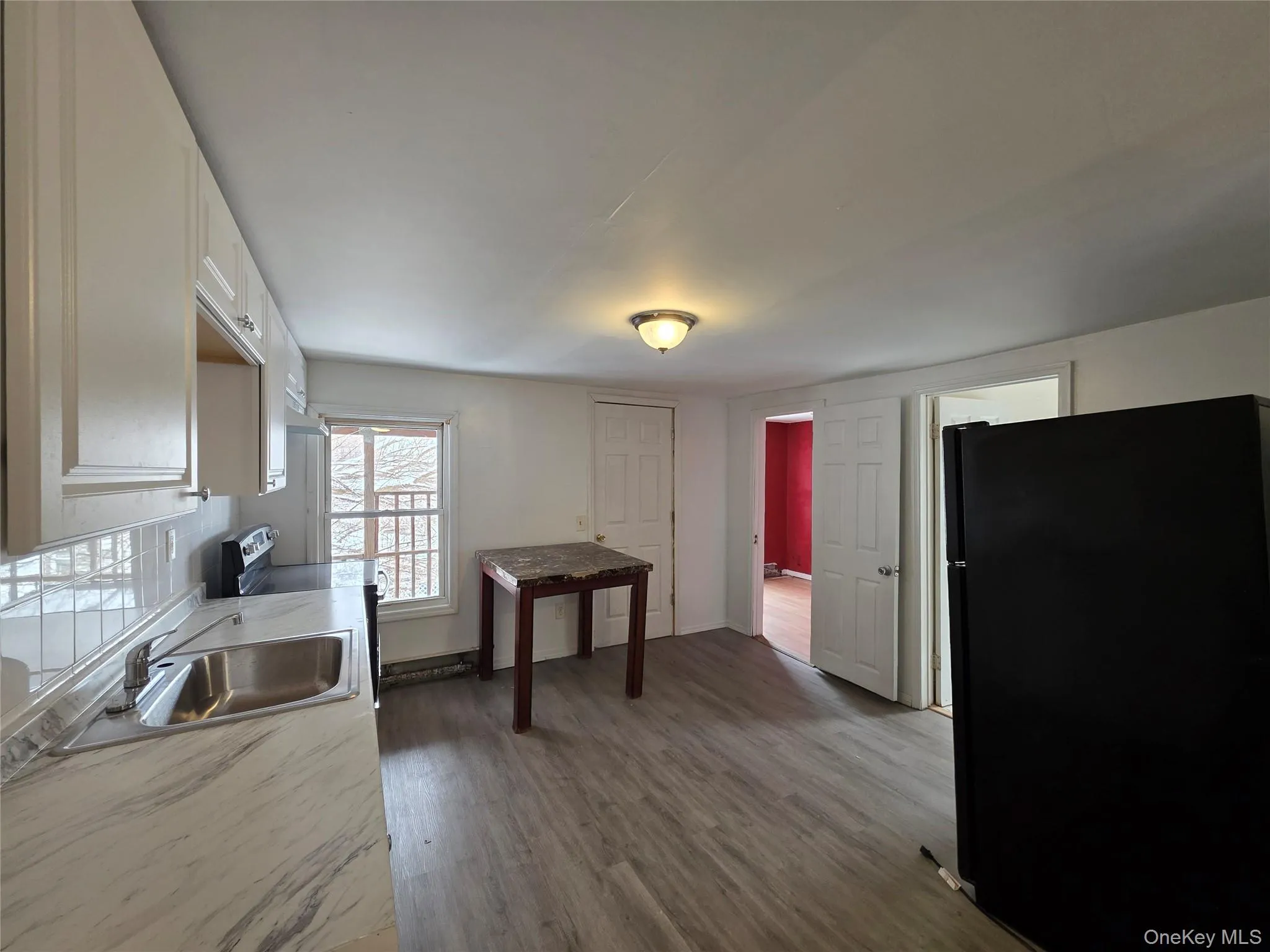 Kitchen featuring freestanding refrigerator, light countertops, white cabinetry, dark wood-style flooring, and stainless steel electric stove Kitchen featuring freestanding refrigerator, light countertops, white cabinetry, dark wood-style flooring, and stainless steel electric stove
