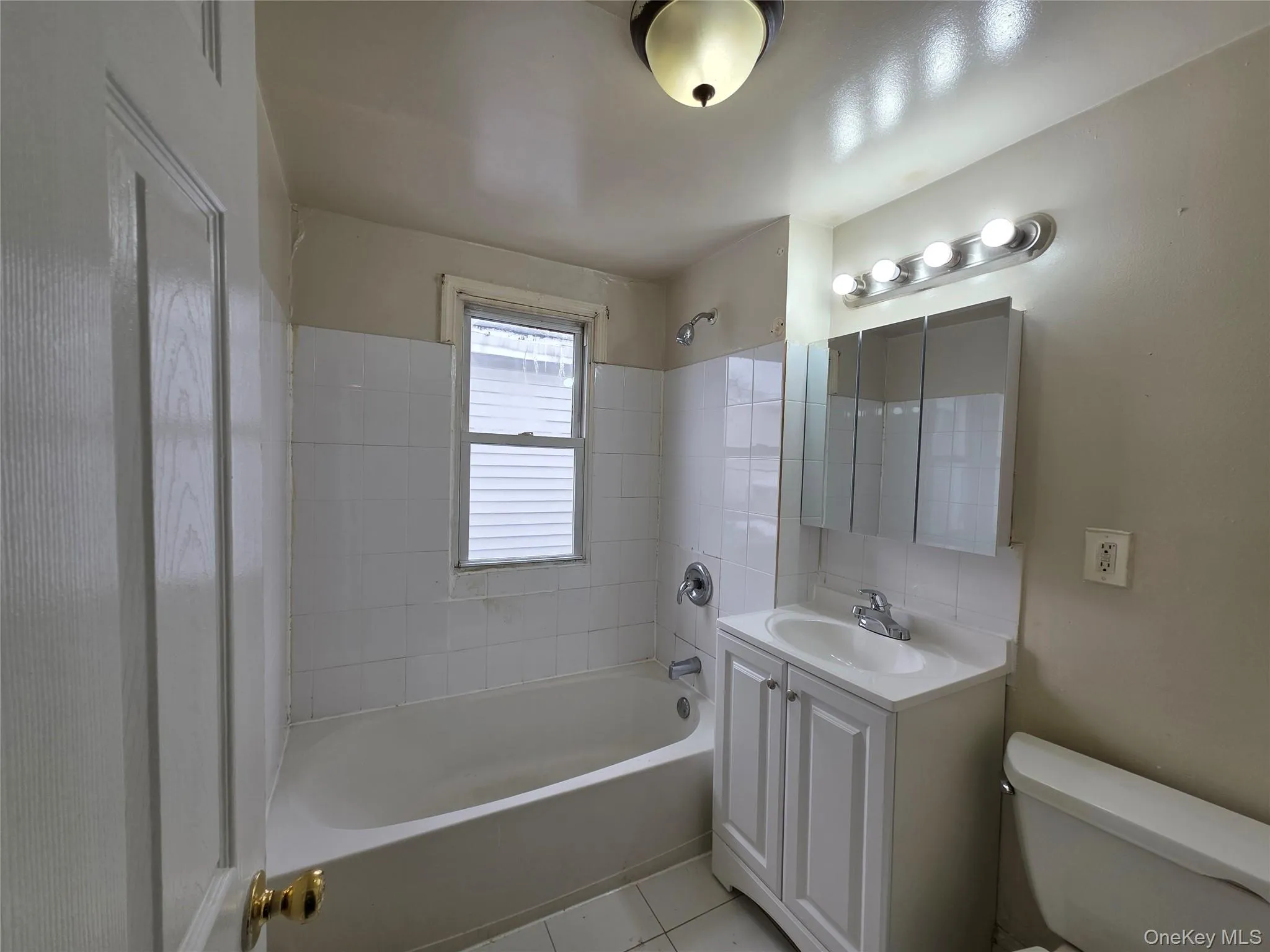 Bathroom featuring vanity, shower / bath combination, and light tile patterned floors Bathroom featuring vanity, shower / bath combination, and light tile patterned floors