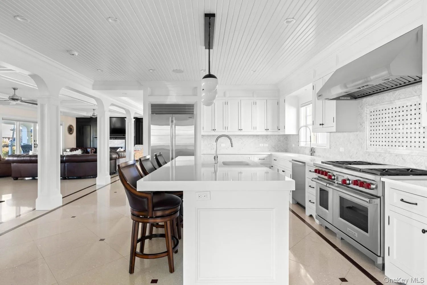 Kitchen featuring white cabinetry, a breakfast bar, high end appliances, an island with sink, and wood ceiling Kitchen featuring white cabinetry, a breakfast bar, high end appliances, an island with sink, and wood ceiling