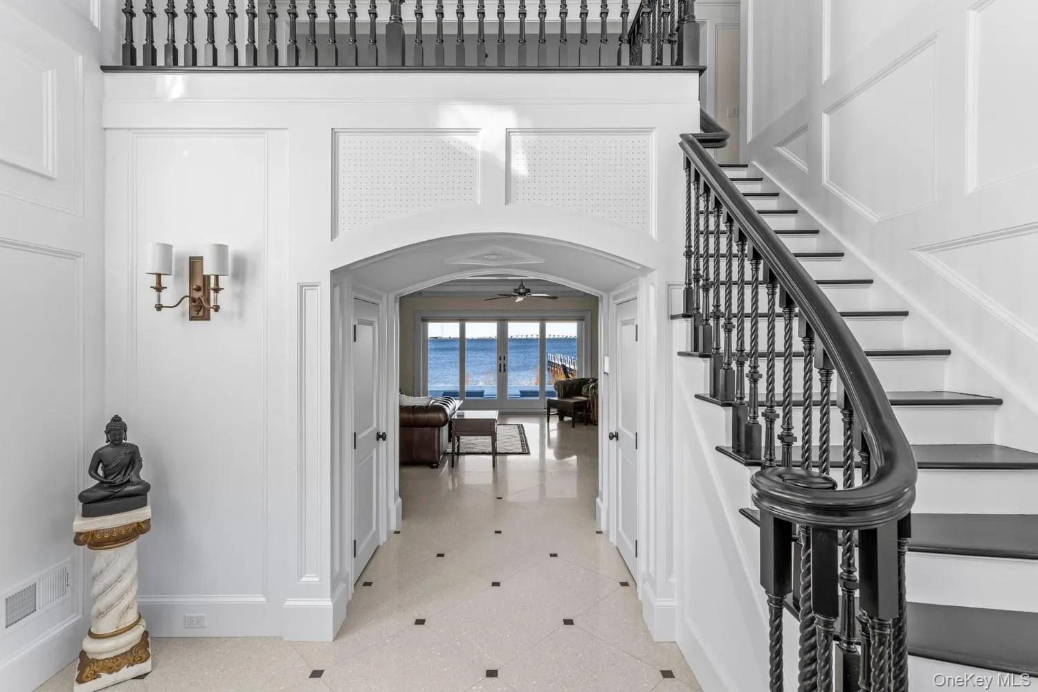 Foyer entrance featuring arched walkways, a ceiling fan, stairway, and a decorative wall Foyer entrance featuring arched walkways, a ceiling fan, stairway, and a decorative wall