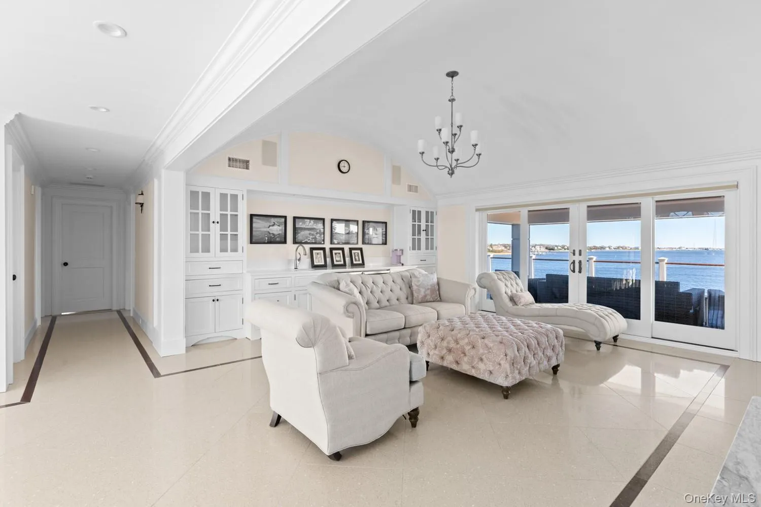 Living room with a water view, a chandelier, crown molding, french doors, and vaulted ceiling Living room with a water view, a chandelier, crown molding, french doors, and vaulted ceiling