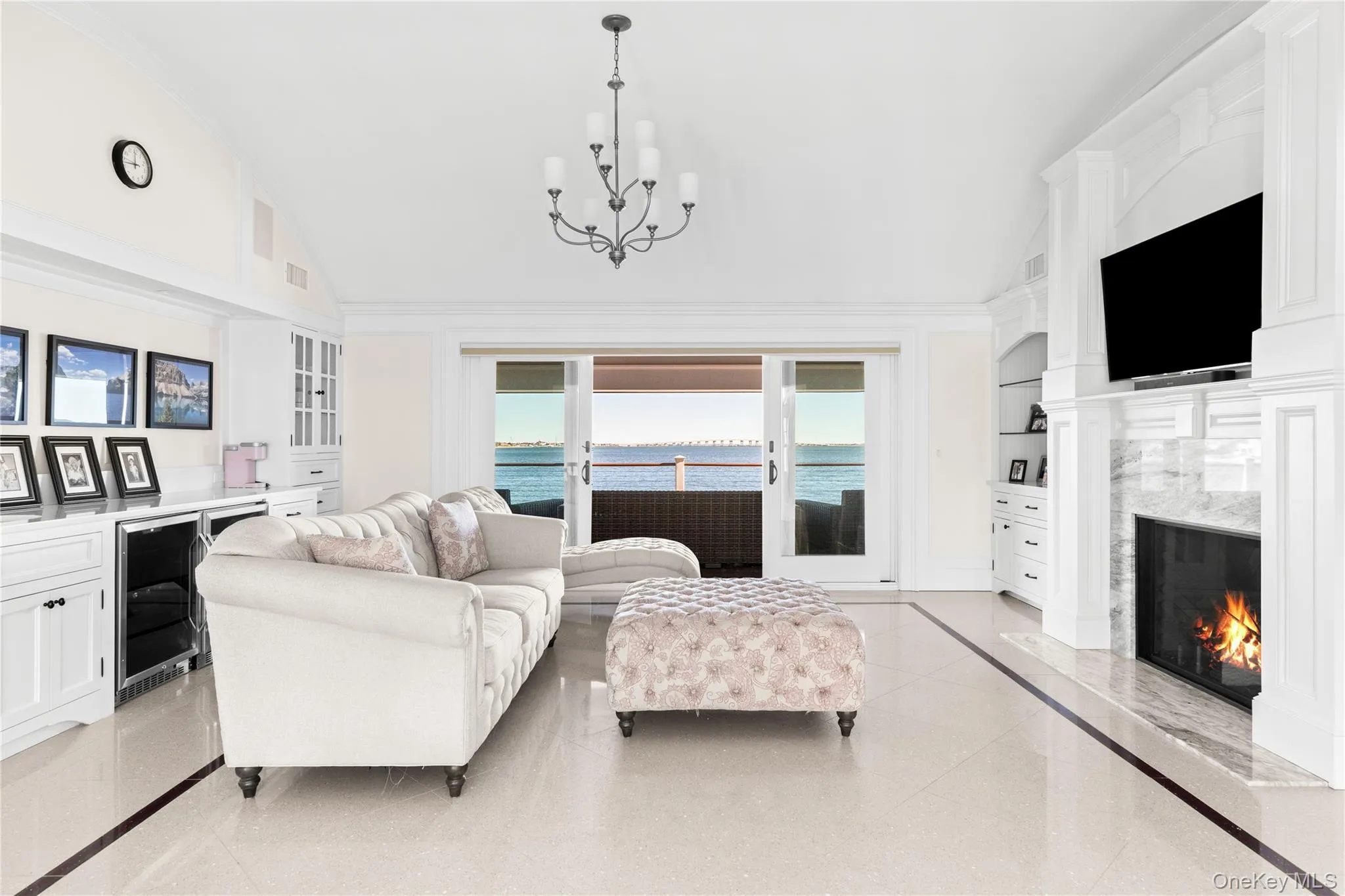 Living room featuring built in features, a premium fireplace, lofted ceiling, beverage cooler, and a chandelier Living room featuring built in features, a premium fireplace, lofted ceiling, beverage cooler, and a chandelier