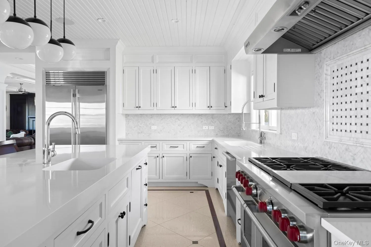 Kitchen with high end appliances, exhaust hood, white cabinetry, wood ceiling, and light stone countertops Kitchen with high end appliances, exhaust hood, white cabinetry, wood ceiling, and light stone countertops