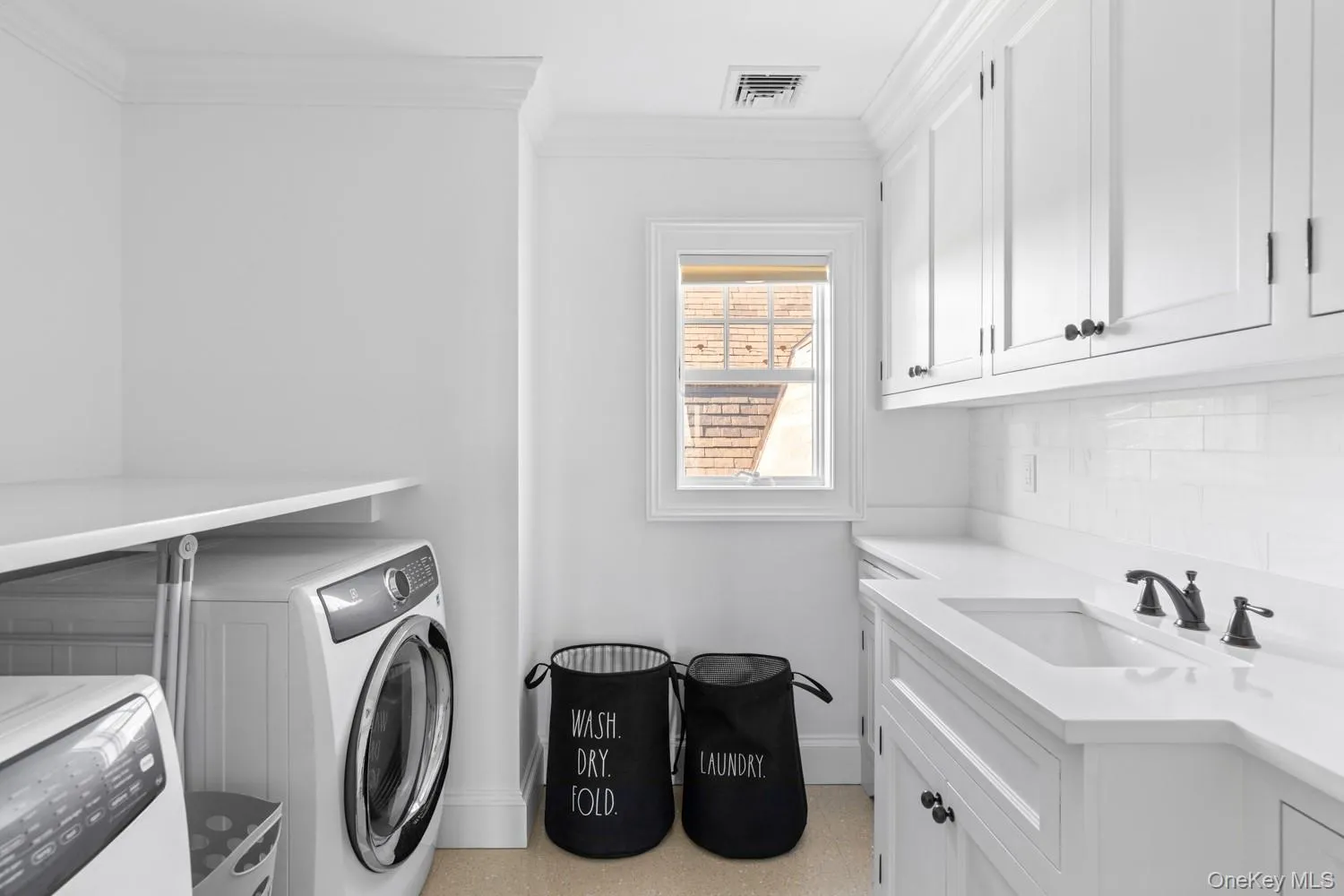Laundry room featuring washing machine and clothes dryer, cabinet space, and ornamental molding Laundry room featuring washing machine and clothes dryer, cabinet space, and ornamental molding
