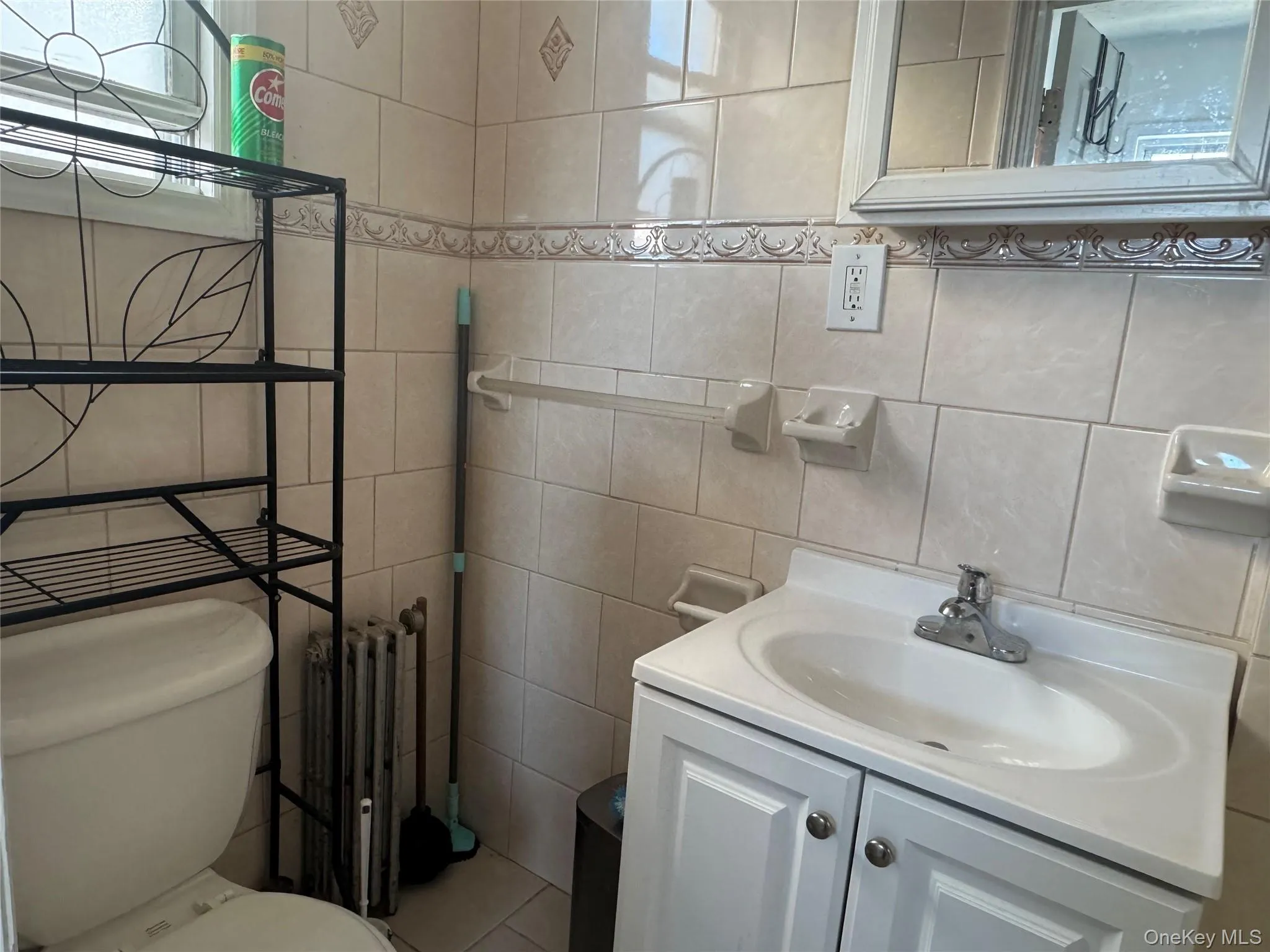 Half bath with vanity, radiator, and tile walls Half bath with vanity, radiator, and tile walls