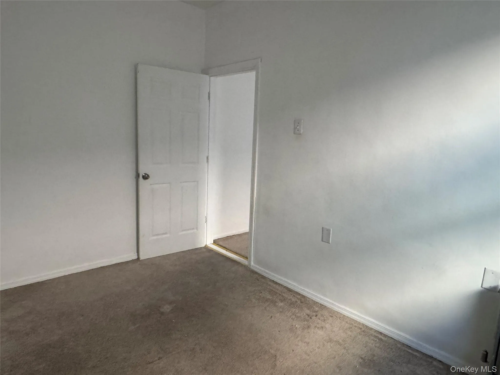 Unfurnished room featuring dark carpet and baseboards Unfurnished room featuring dark carpet and baseboards