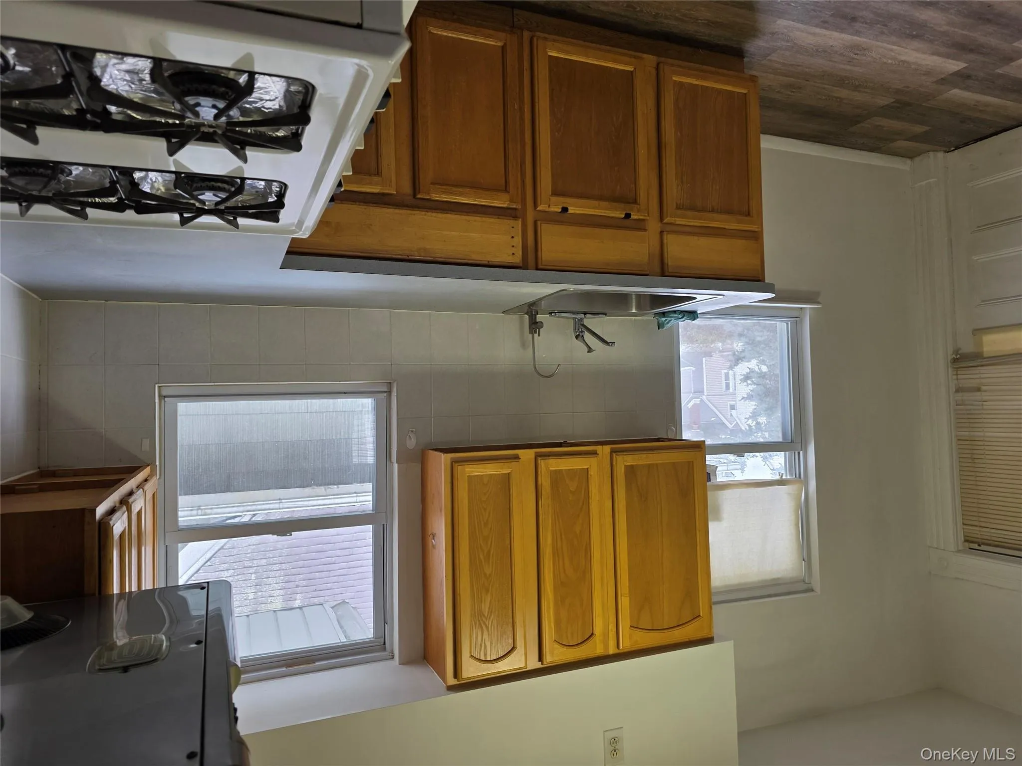 Kitchen featuring decorative backsplash, extractor fan, range, brown cabinets, and light countertops Kitchen featuring decorative backsplash, extractor fan, range, brown cabinets, and light countertops