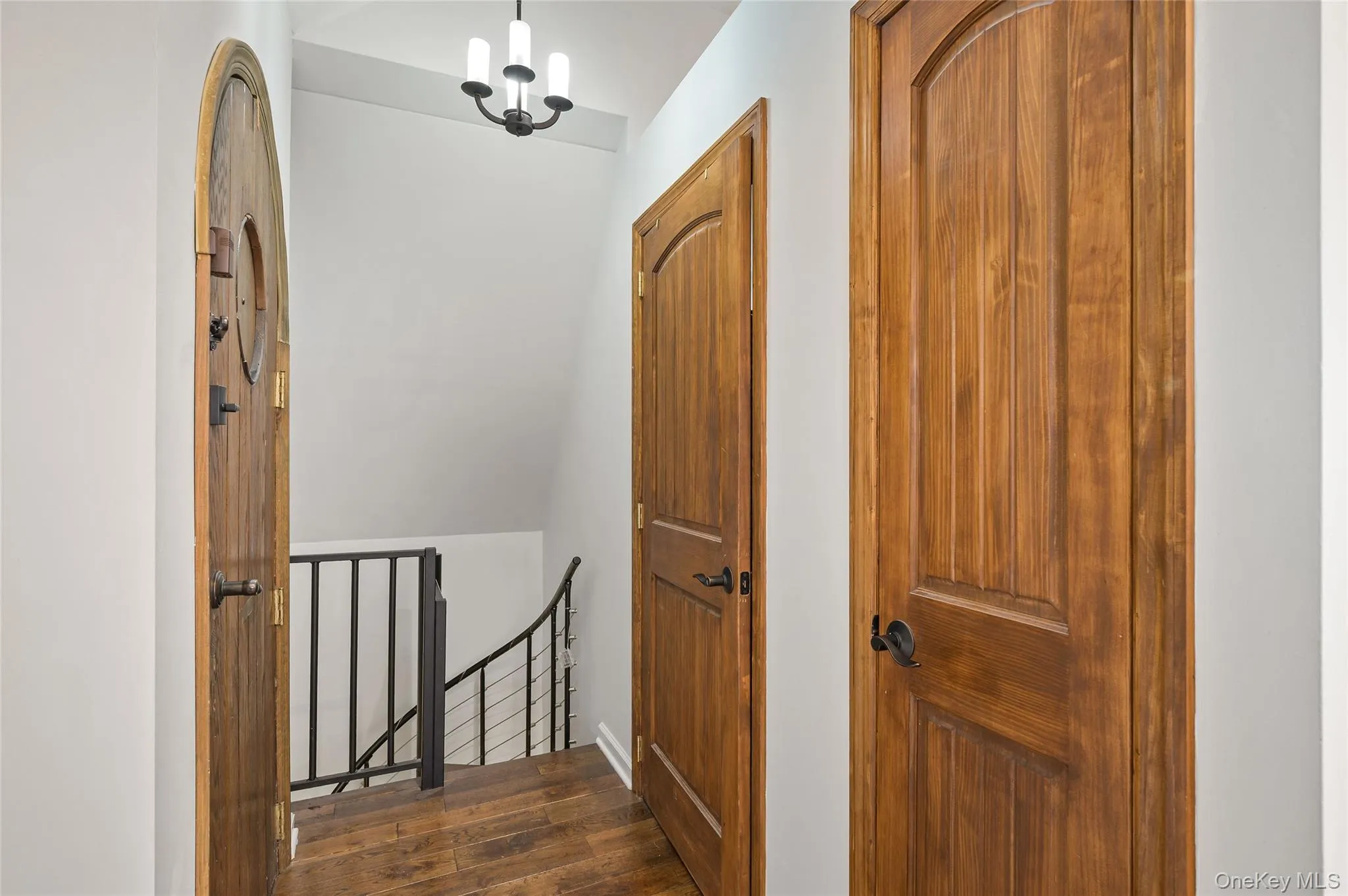 Hall with an upstairs landing, a chandelier, and dark wood-style floors Hall with an upstairs landing, a chandelier, and dark wood-style floors