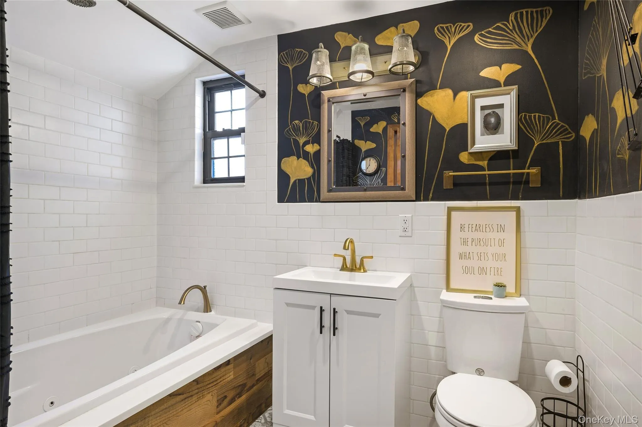 Full bathroom with tile walls, vanity, and a combined bath / shower with jetted tub Full bathroom with tile walls, vanity, and a combined bath / shower with jetted tub