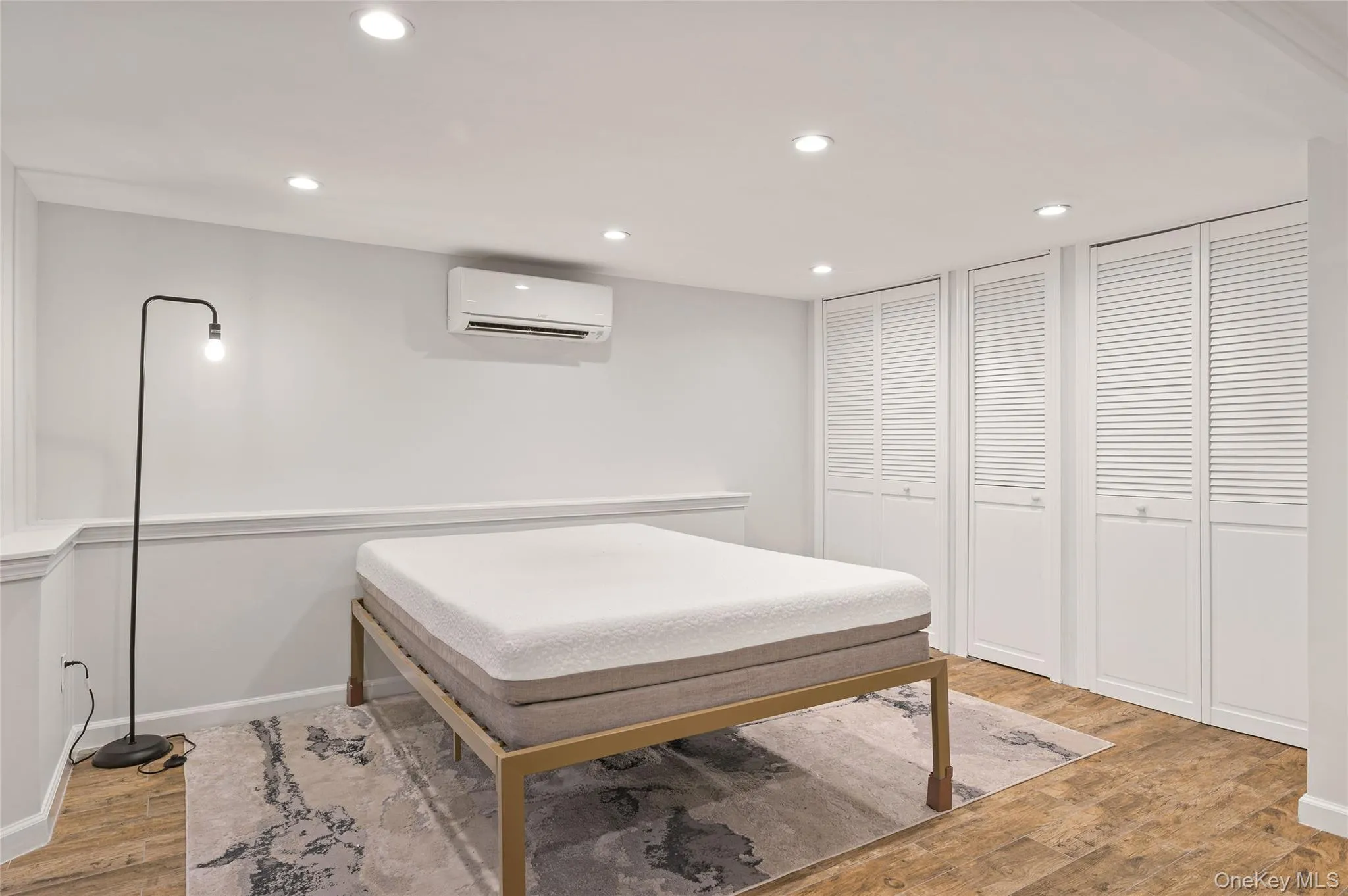 Bedroom featuring recessed lighting, light wood-style floors, multiple closets, and a wall mounted AC Bedroom featuring recessed lighting, light wood-style floors, multiple closets, and a wall mounted AC