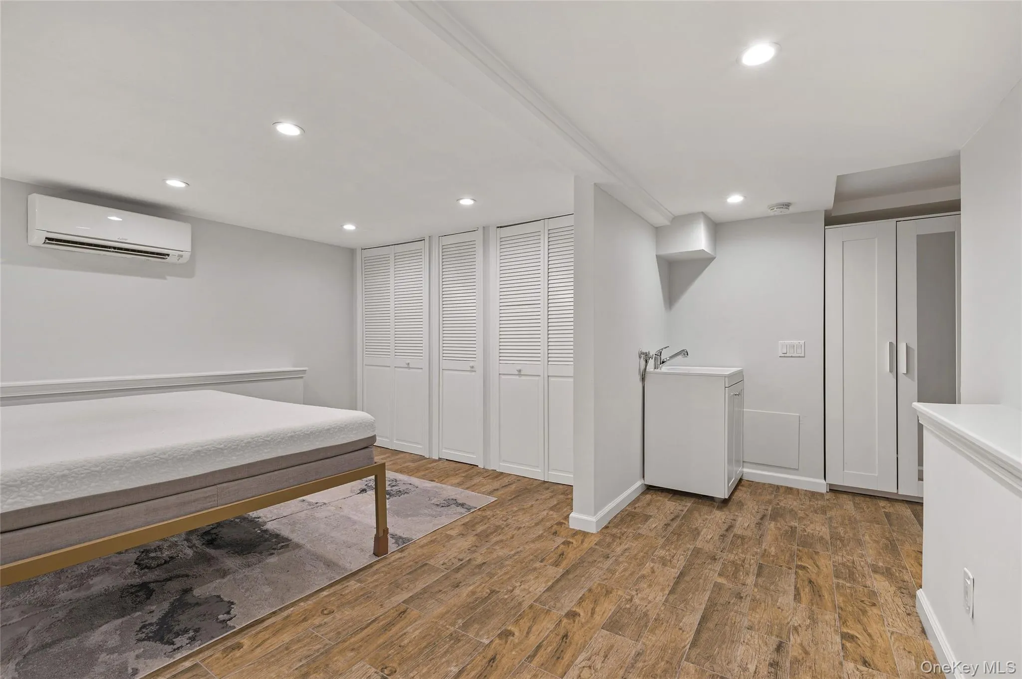 Bedroom with dark wood-type flooring, recessed lighting, a wall unit AC, and multiple closets Bedroom with dark wood-type flooring, recessed lighting, a wall unit AC, and multiple closets
