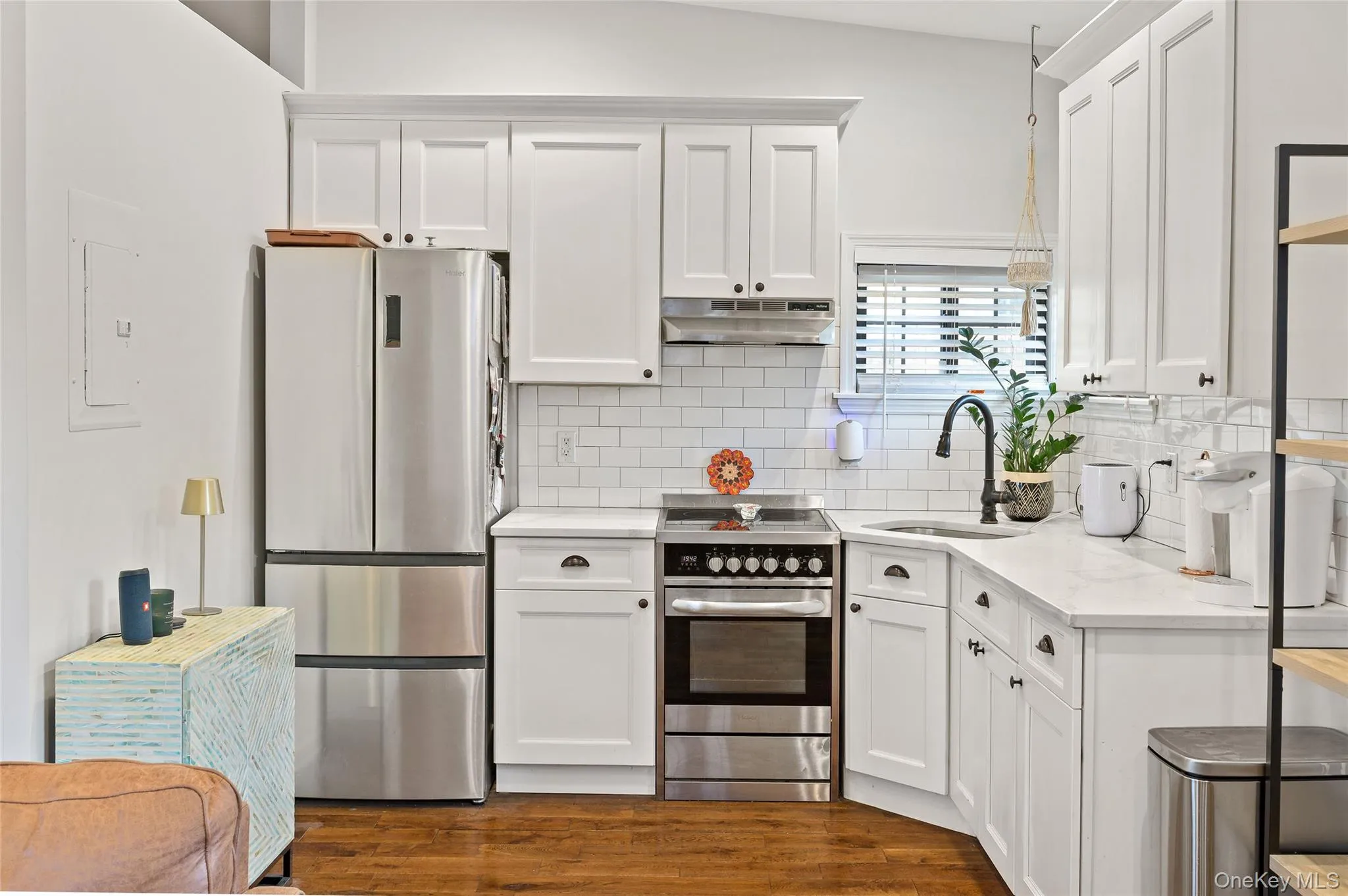 Kitchen featuring stainless steel appliances, light stone countertops, under cabinet range hood, dark wood-type flooring, and white cabinets Kitchen featuring stainless steel appliances, light stone countertops, under cabinet range hood, dark wood-type flooring, and white cabinets