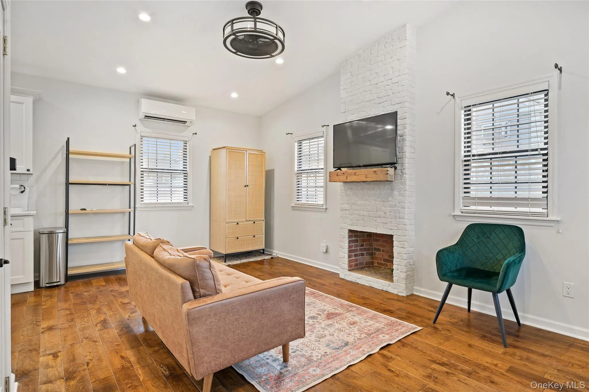 Living area featuring lofted ceiling, a brick fireplace, dark wood finished floors, recessed lighting, and an AC wall unit Living area featuring lofted ceiling, a brick fireplace, dark wood finished floors, recessed lighting, and an AC wall unit