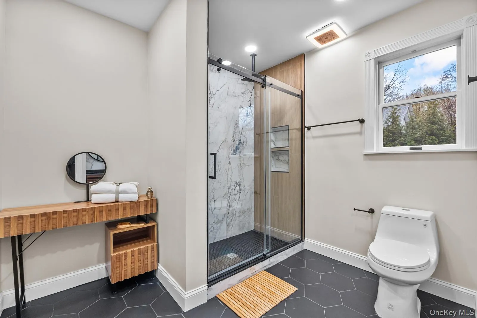 Bathroom with dark tile patterned floors, a marble finish shower, and recessed lighting Bathroom with dark tile patterned floors, a marble finish shower, and recessed lighting
