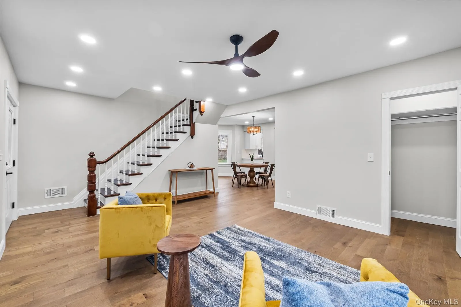 Living room featuring recessed lighting, light wood-type flooring, ceiling fan, stairway, and a chandelier Living room featuring recessed lighting, light wood-type flooring, ceiling fan, stairway, and a chandelier