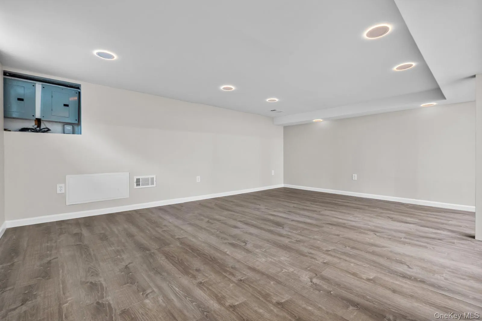 Basement with electric panel, light wood-style flooring, and recessed lighting Basement with electric panel, light wood-style flooring, and recessed lighting