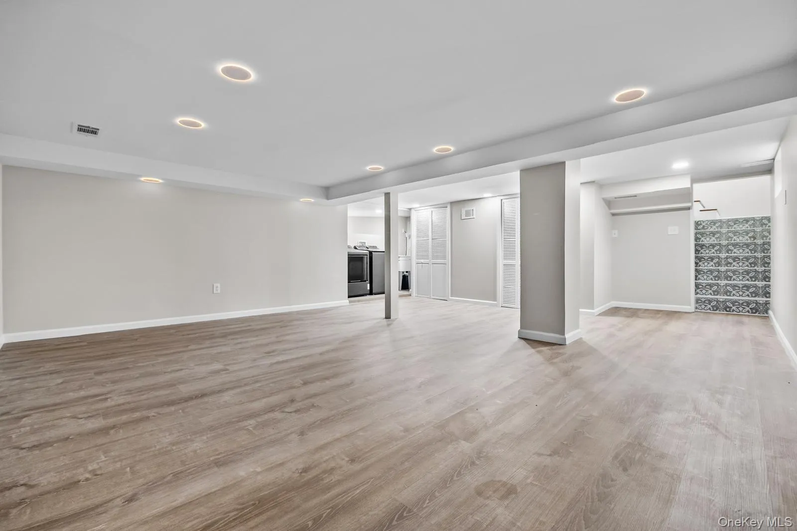 Finished basement with stairway, recessed lighting, light wood-style flooring, and washer / clothes dryer Finished basement with stairway, recessed lighting, light wood-style flooring, and washer / clothes dryer