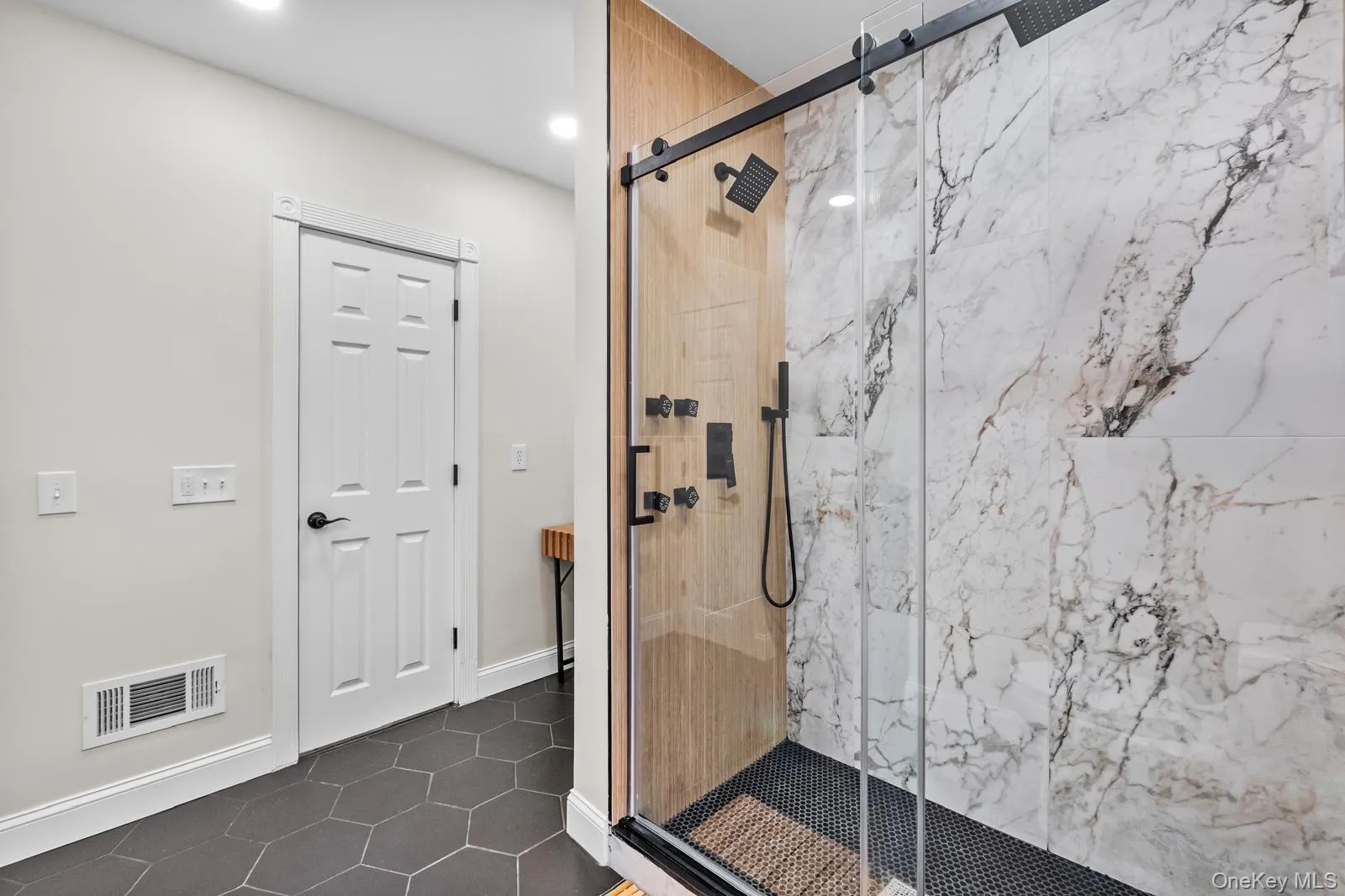 Bathroom featuring a marble finish shower and dark tile patterned flooring Bathroom featuring a marble finish shower and dark tile patterned flooring