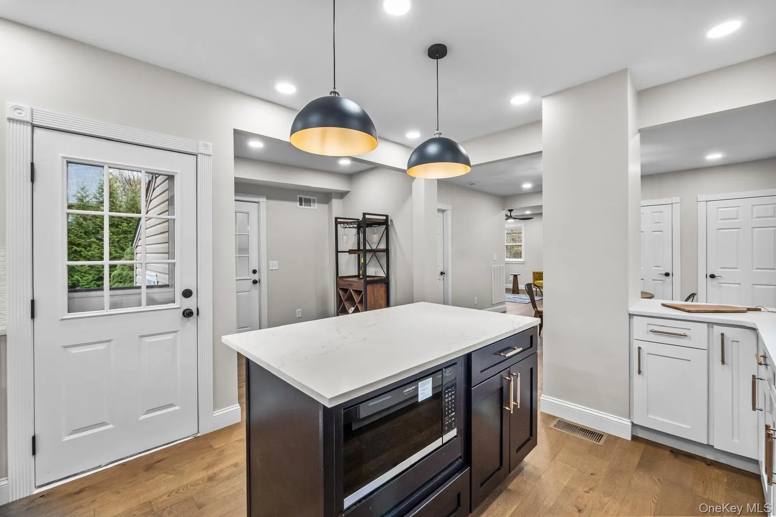 Kitchen with built in microwave, a center island, hanging light fixtures, white cabinets, and light stone counters Kitchen with built in microwave, a center island, hanging light fixtures, white cabinets, and light stone counters