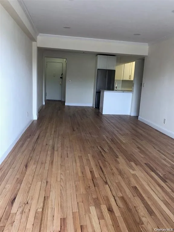 Unfurnished living room featuring crown molding and dark wood finished floors Unfurnished living room featuring crown molding and dark wood finished floors