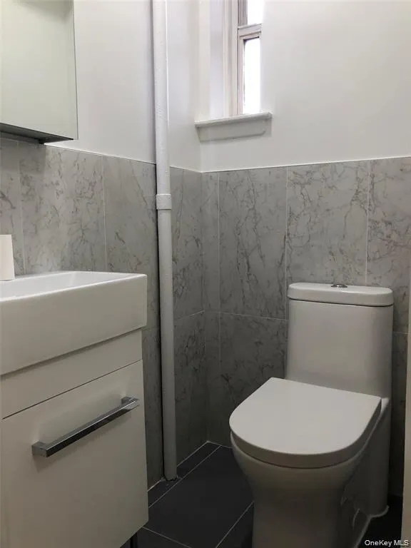Bathroom with tile walls, a wainscoted wall, and vanity Bathroom with tile walls, a wainscoted wall, and vanity
